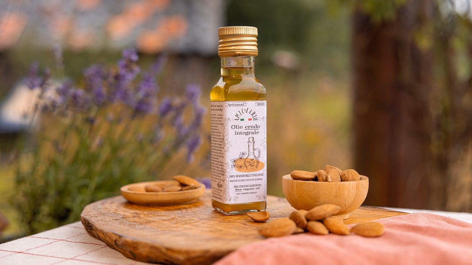 Olio crudo di mandorle italiane con mandorle intere su tavola rustica | Raw Italian almond oil with whole almonds on rustic table