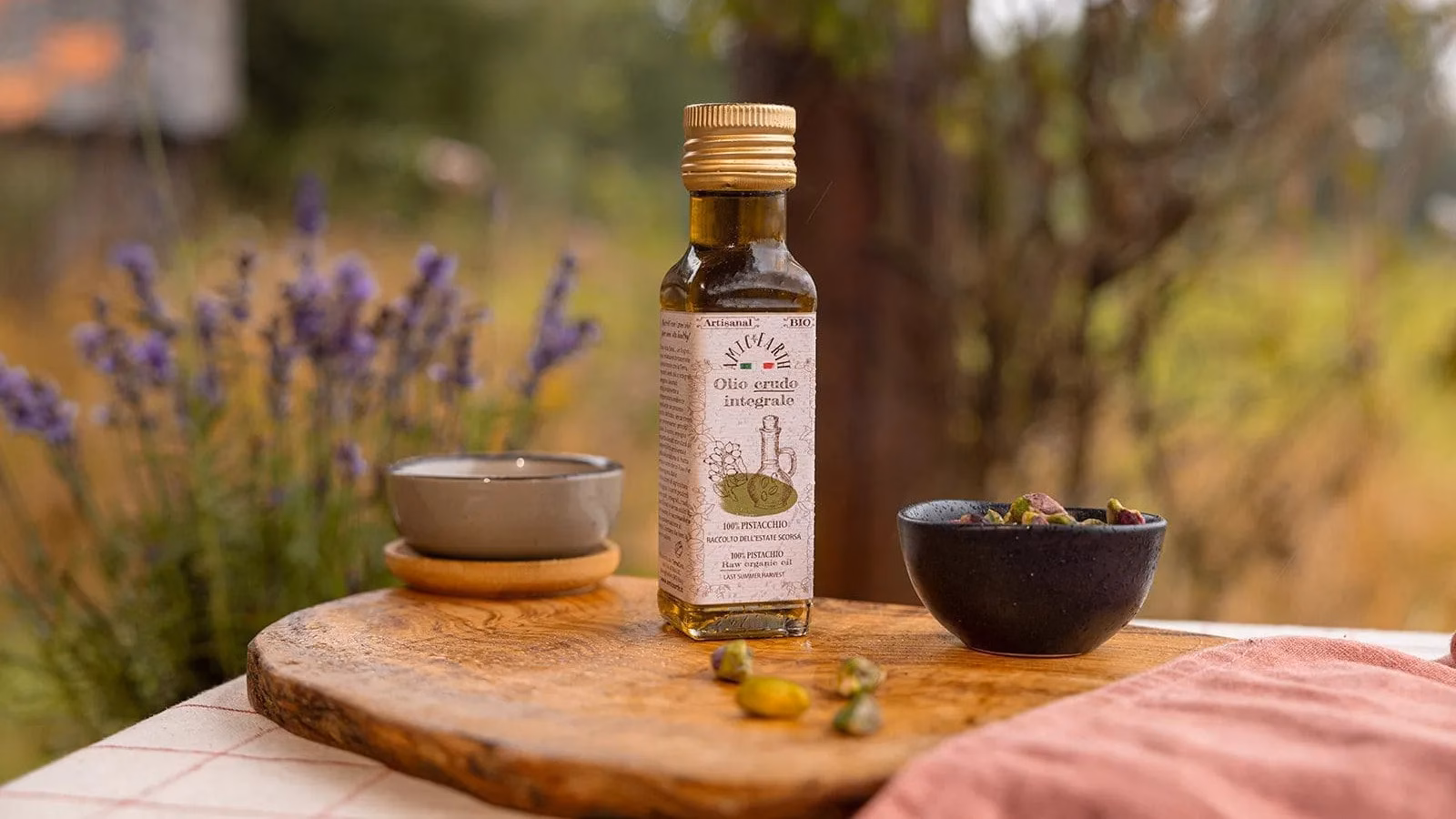 Bottiglia di olio crudo integrale di pistacchi con ciotola di pistacchi su tagliere di legno | Bottle of raw whole pistachio oil with pistachio bowl on a wooden board