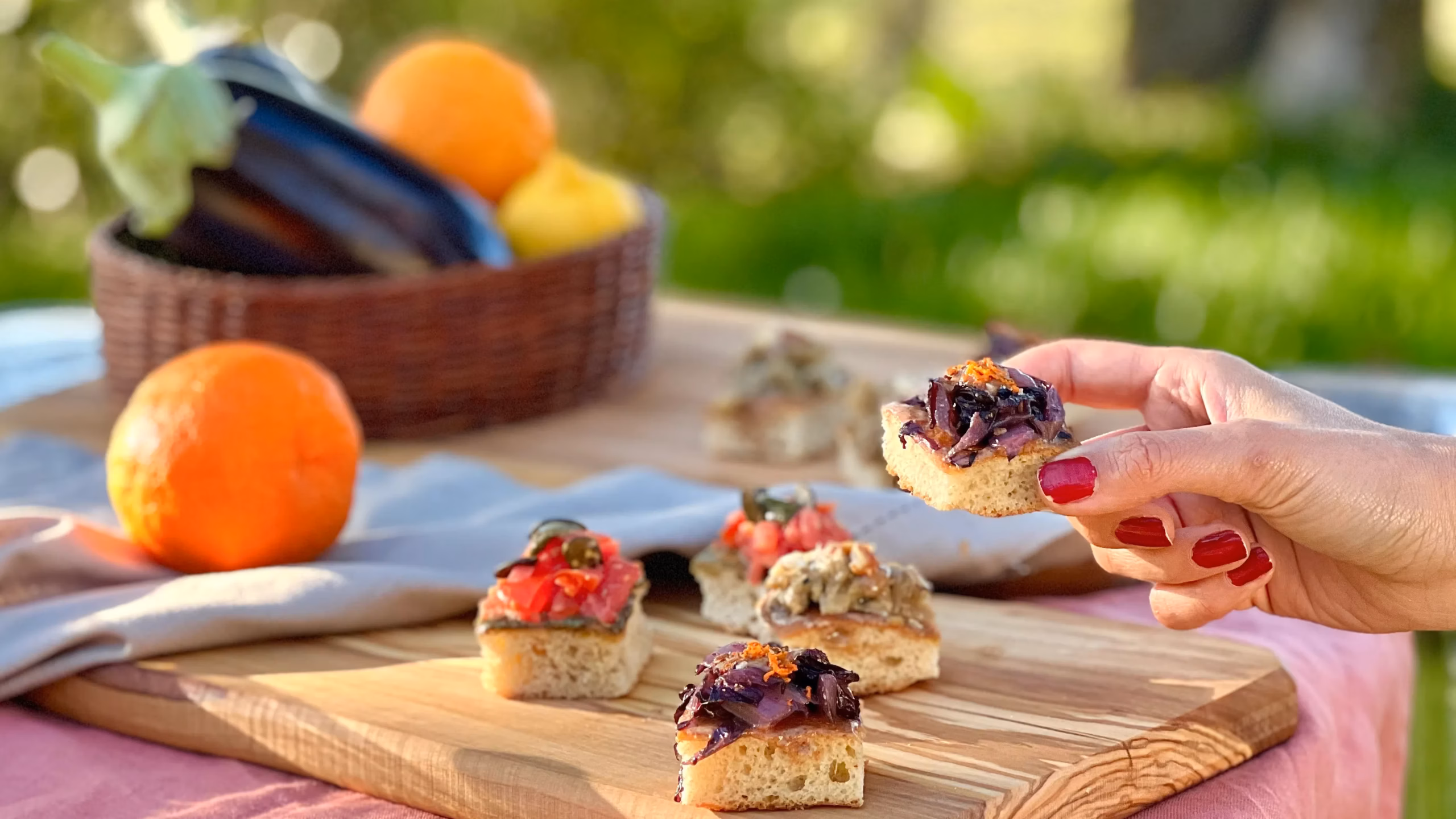 Crostini colorati su tagliere con verdure di stagione e mano femminile | Colorful crostini on a wooden board with seasonal vegetables and a woman's hand