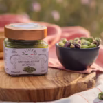 Burro crudo integrale di pistacchi su tagliere in legno con ciotola di pistacchi | Raw whole pistachio butter on wooden board with a bowl of pistachios