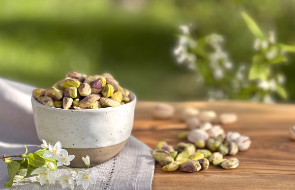 Pistacchi crudi interi senza guscio | Whole raw shelled pistachios Pistacchi sgusciati biologici in ciotola all’aperto | Shelled organic pistachios in outdoor bowl